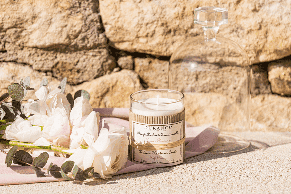 bougie artisanale douce pivoine sur un sol avec une pivoine et une nappe