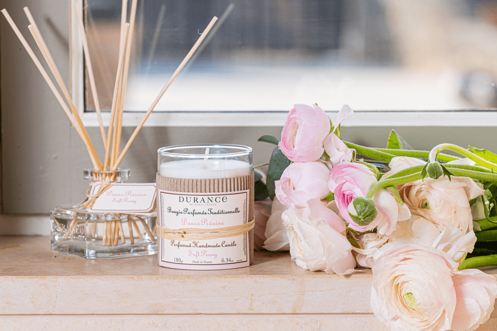 bougie artisanale douce pivoine sur un rebord de fenêtre avec un bouquet de pivoine