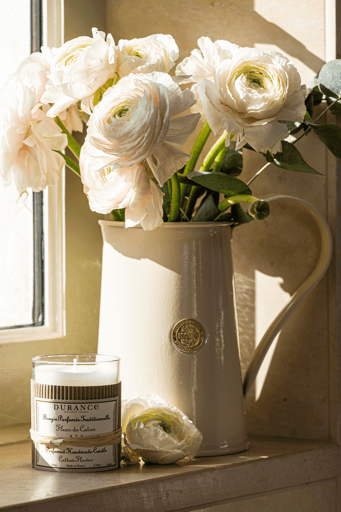 bougie artisanale douce pivoine sur un rebord de fenêtre avec un bouquet de pivoine